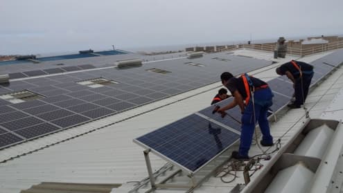 Operarios montando paneles fotovoltaicos en cubierta